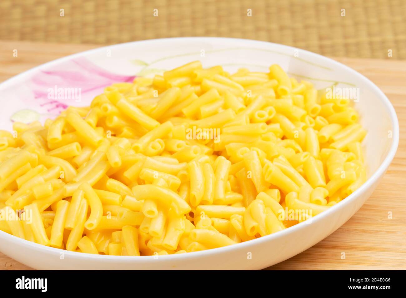 Teller voll mit köstlichen Macaroni und Käse auf einem hölzernen Hintergrund Stockfoto