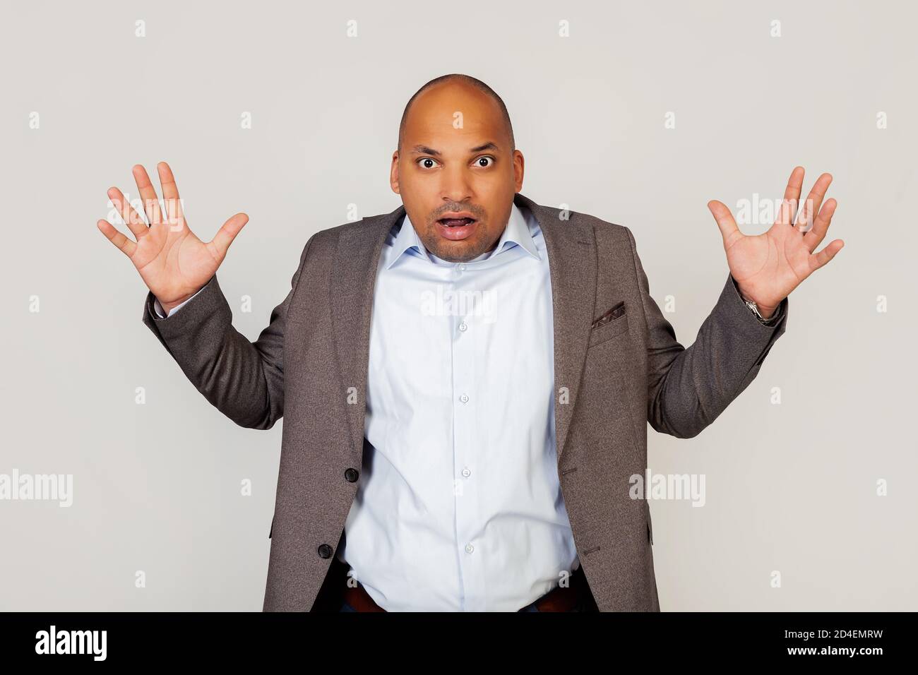 Verärgert Mann afroamerikanischen Geschäftsmann in einer Jacke, macht eine unzufrieden Geste, breitet seine Arme und schreit wild, wütend und wütend emotional hob seine Handflächen nach oben und schreit heiß in die Kamera. Stockfoto