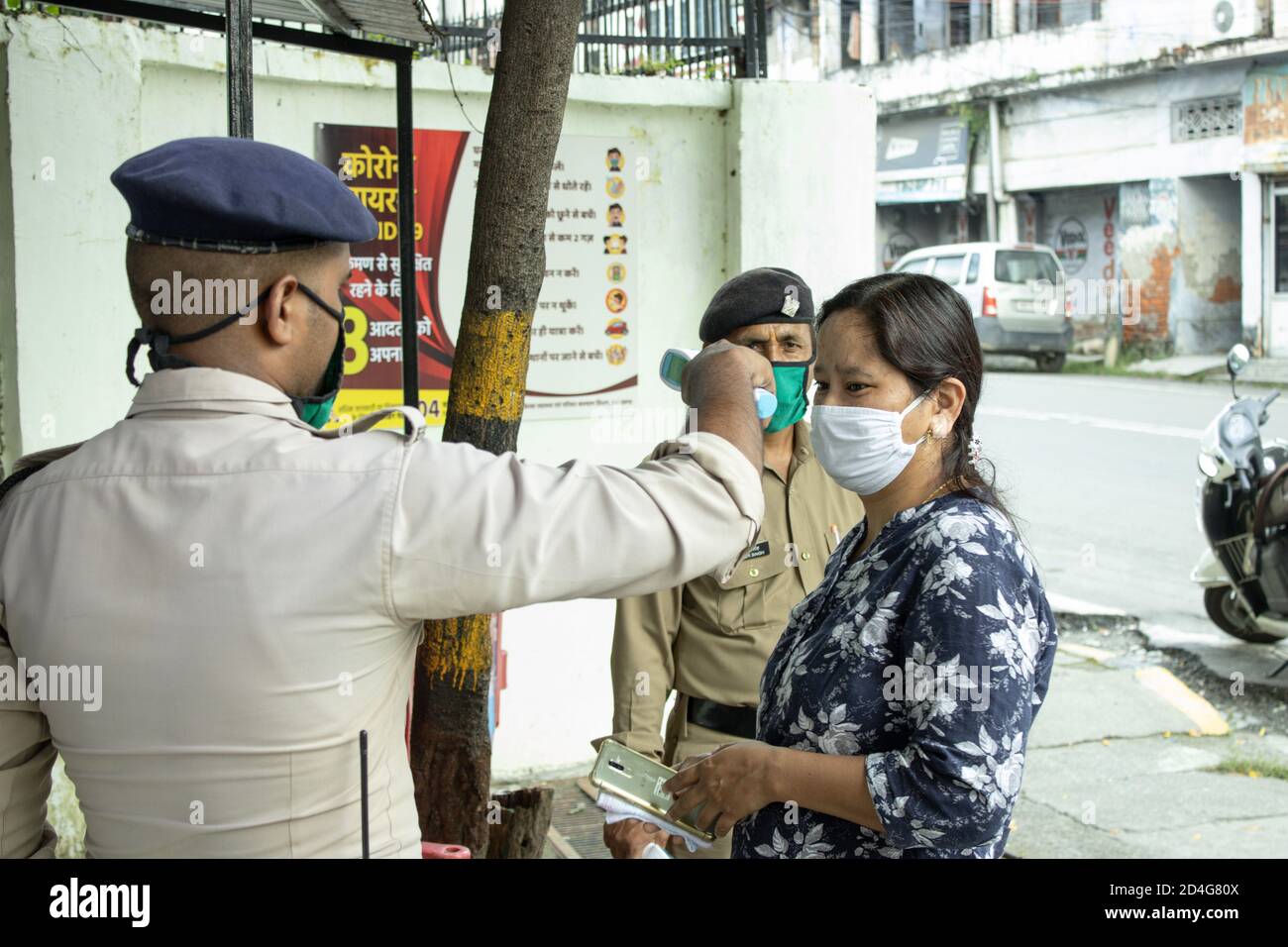 Ein Sicherheitswächter, der die Temperatur einer Dame überprüft, bevor er die Erlaubnis erteilt, wegen einer Corona-Pandemie in Indien ins Büro einzutreten. Stockfoto