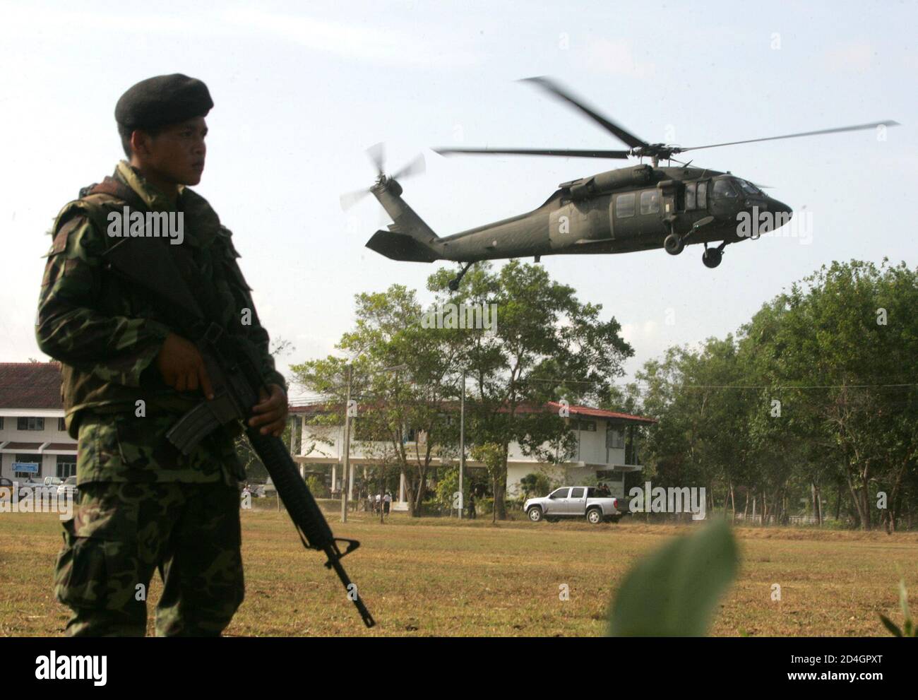 Ein Soldat steht Wache von einem Militärhubschrauber, verwendet, um Verkehr Premierminister Thaksin Shinawatra während seiner zweitägigen Reise über den unruhigen muslimischen Süden in Yala Provinz, 1.200 km (750 Meilen) südlich von Bangkok 7. Februar 2005. Shinawatra Plan muslimische Dörfer aus der Entwicklungshilfe auszuschließen, wenn sie, separatistische Kämpfer helfen zog heftigen Kritik in der Region. REUTERS/Sukree Sukplang SS/LD Stockfoto
