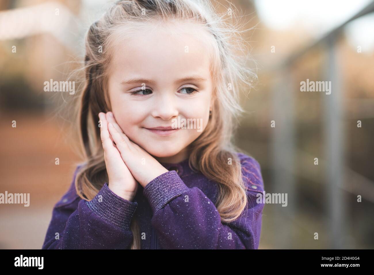 Lächelnd niedlich blonde Baby Mädchen 3-4 Jahre alt posiert im Freien über Stadt im Park Hintergrund aus nächster Nähe. Kind mit gesunder Haut. Kindheit. Herbstsaison. Stockfoto