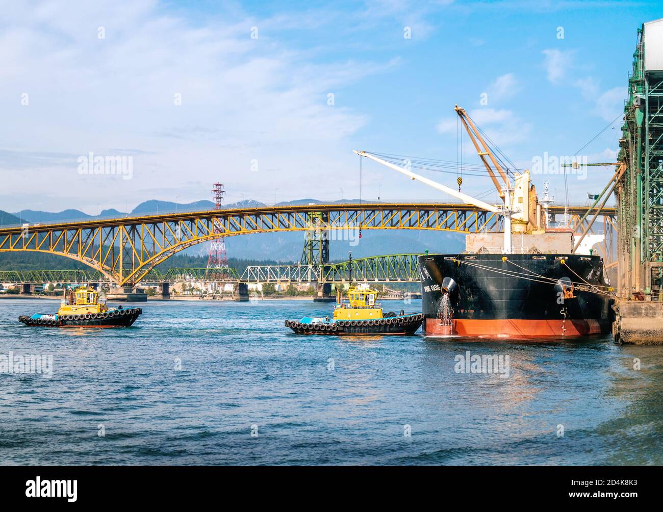 VANCOUVER, BC / KANADA - 29. MAI 2020 - zwei Schlepper nähern sich einem angedockten Tanker an einem Terminal vom Hafen von Vancouver. Stockfoto