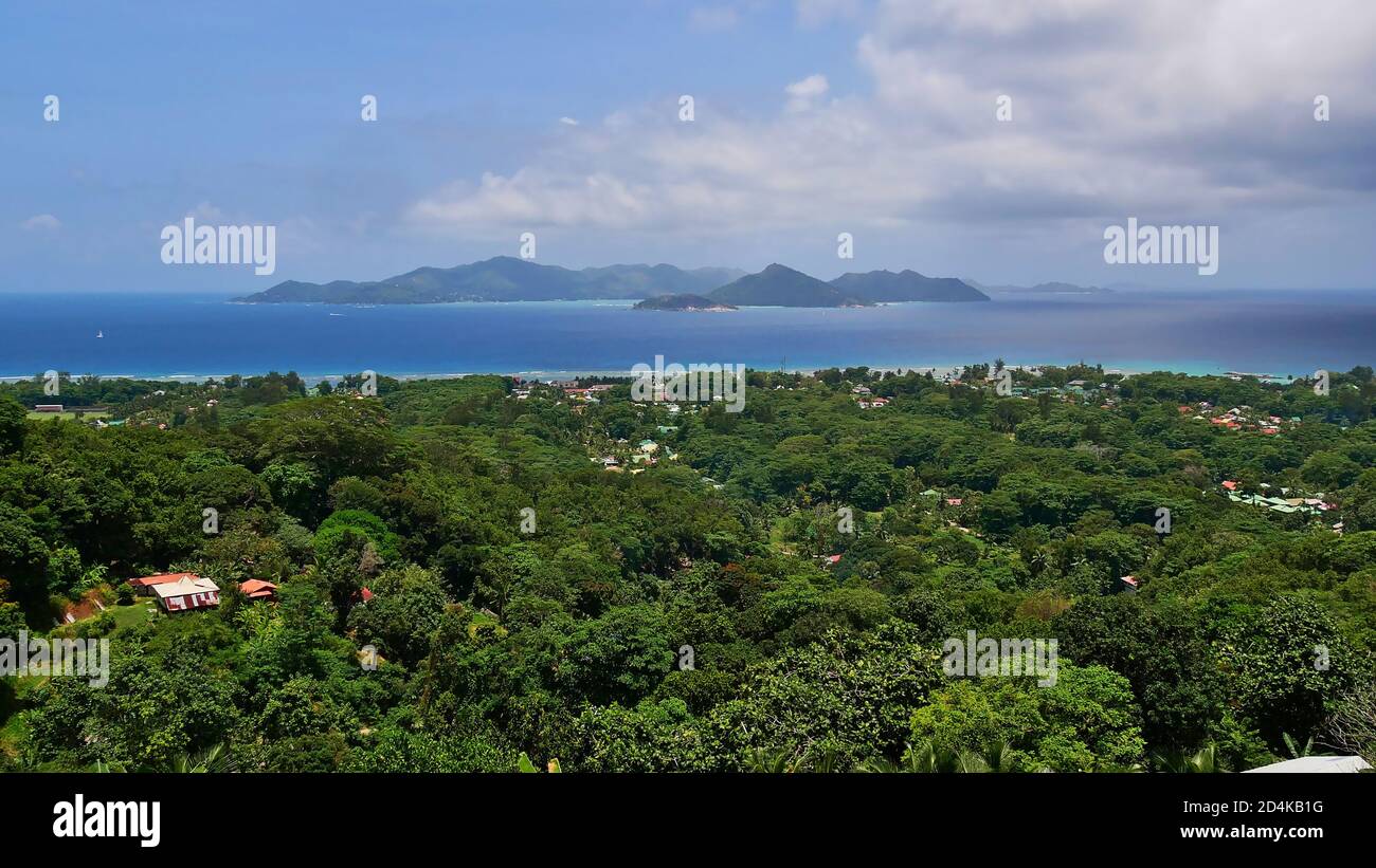 Luftaufnahme der schönen Nordküste der Insel La Digue, Seychellen mit Regenwald, Dorf, Küste und angrenzenden Praslin Insel. Stockfoto