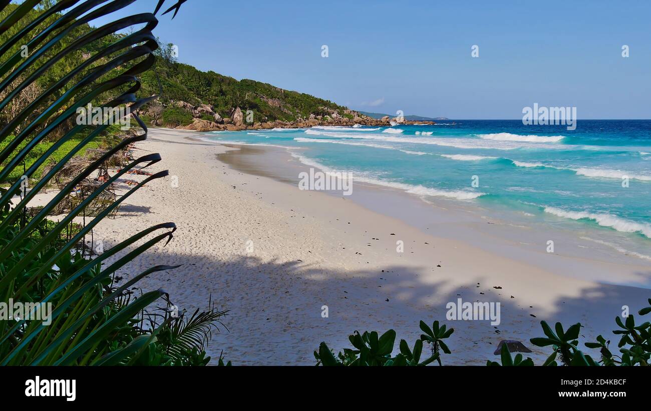 Panoramablick auf den tropischen Strand Petite Anse mit türkisfarbenem Wasser, Granitfelsen und starken Wellen. Stockfoto