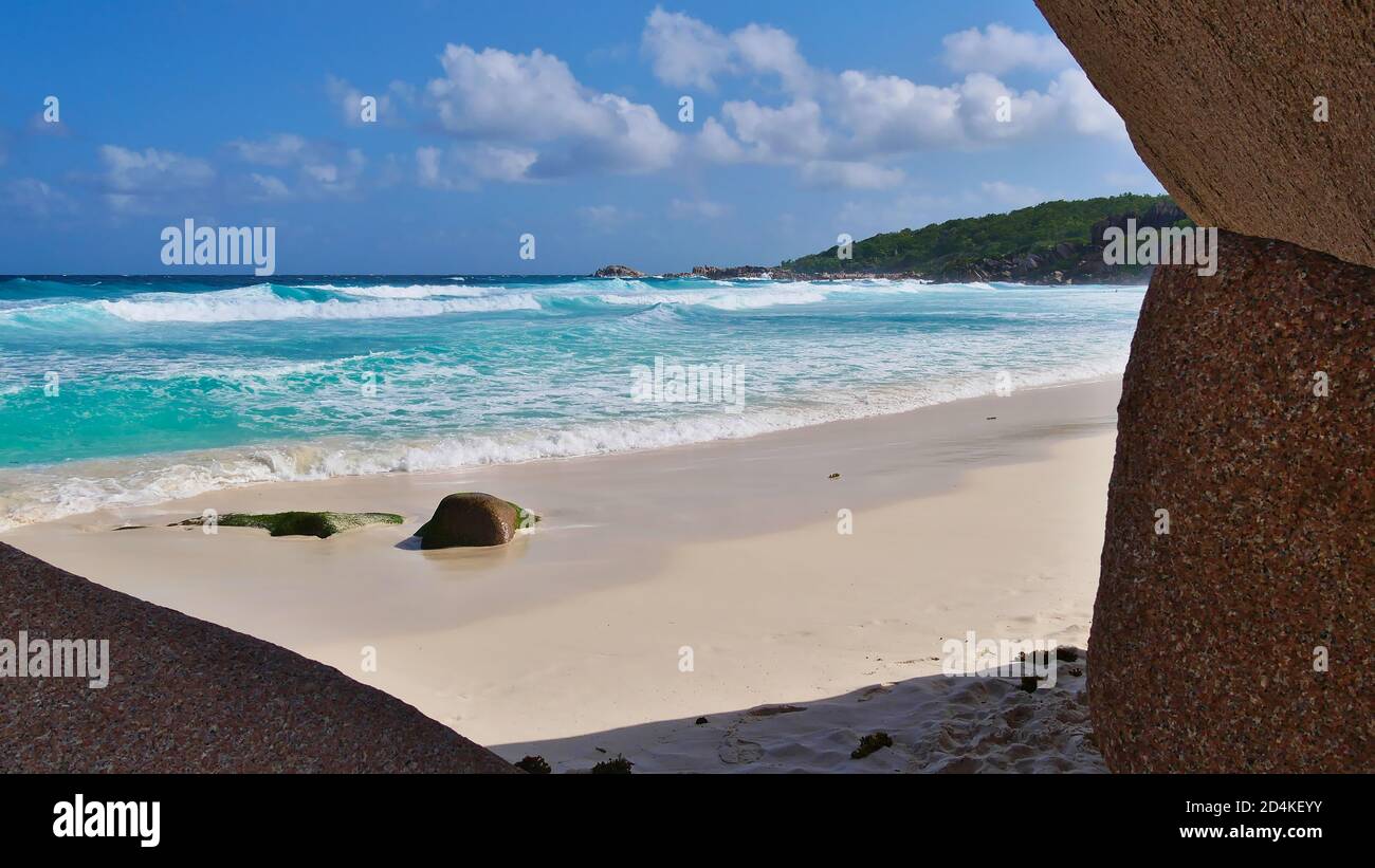 Wunderschöner tropischer Strand Grand Anse mit türkisfarbenem Wasser und starken Wellen im Süden der Insel La Digue, Seychellen, eingerahmt von Granitfelsen. Stockfoto