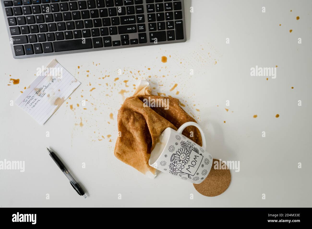 Verschütteter Kaffee, Tastatur, To-Do-Liste und Stift auf weißem Schreibtisch Stockfoto
