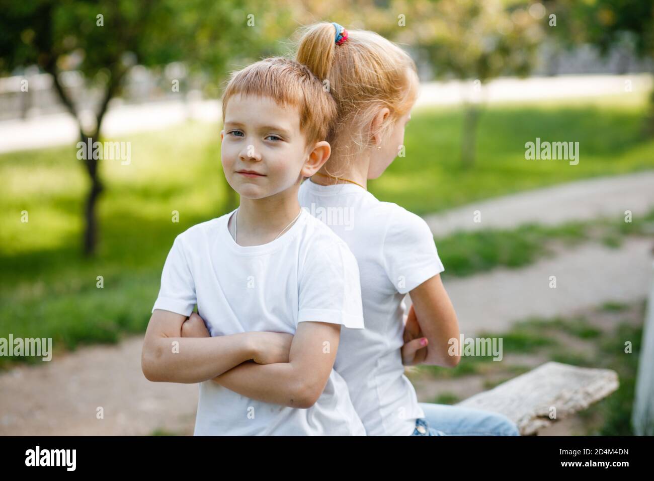 Die Kinder vergehen sich gegenseitig im Park auf der Bank. Stockfoto
