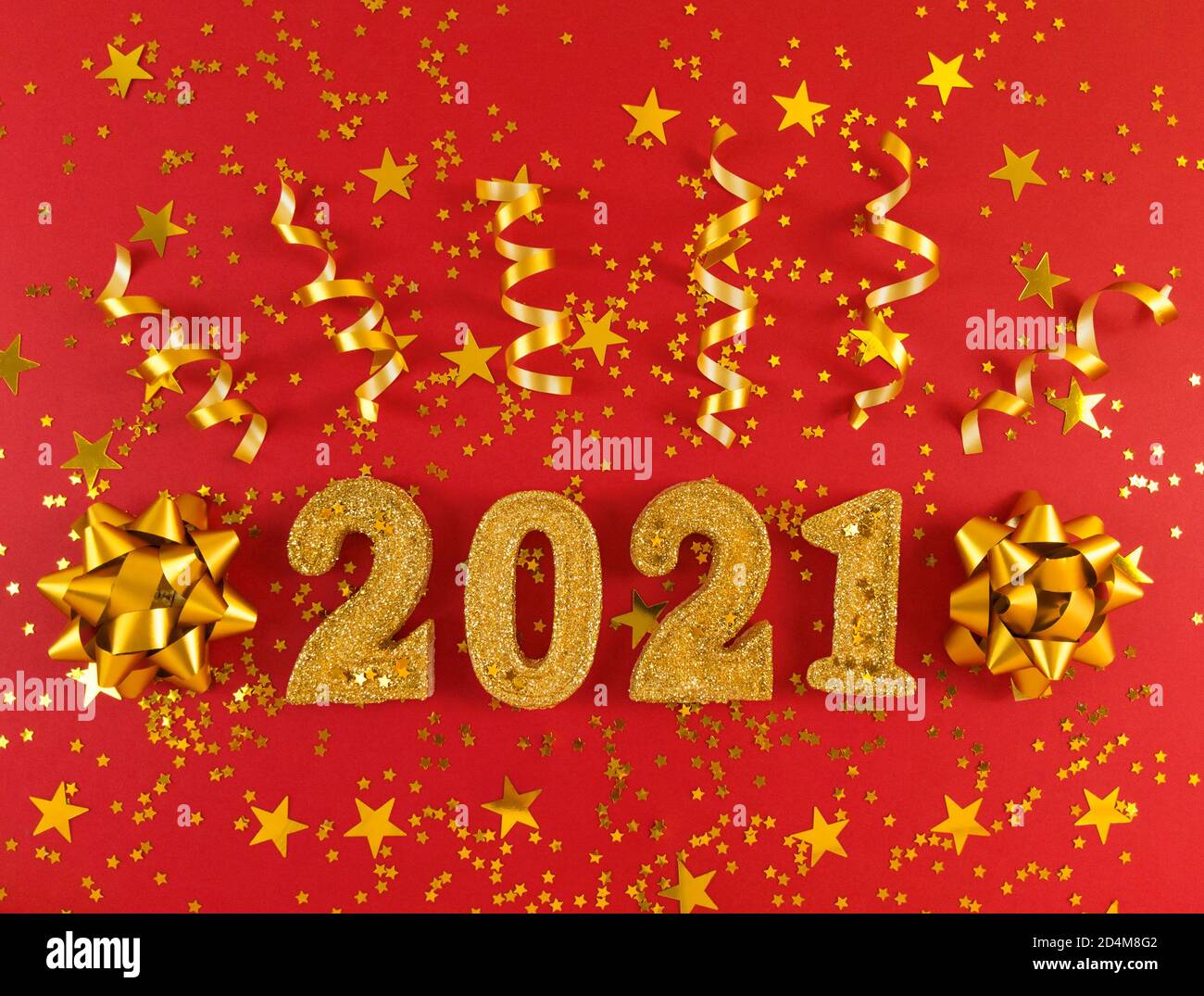 Grußkarte des neuen Jahres 2021. Goldene glitzernde Figuren, Sterne, Schleifen und Bänder auf rotem Hintergrund. Stockfoto