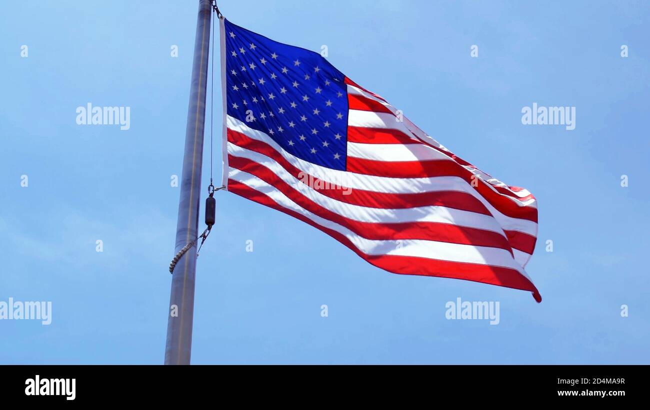 Flagge der Vereinigten Staaten von Amerika winkt an einem sonnigen Tag gegen den blauen Himmel, Blick aus dem niedrigen Winkel. USA, USA, USA, USA. Stockfoto