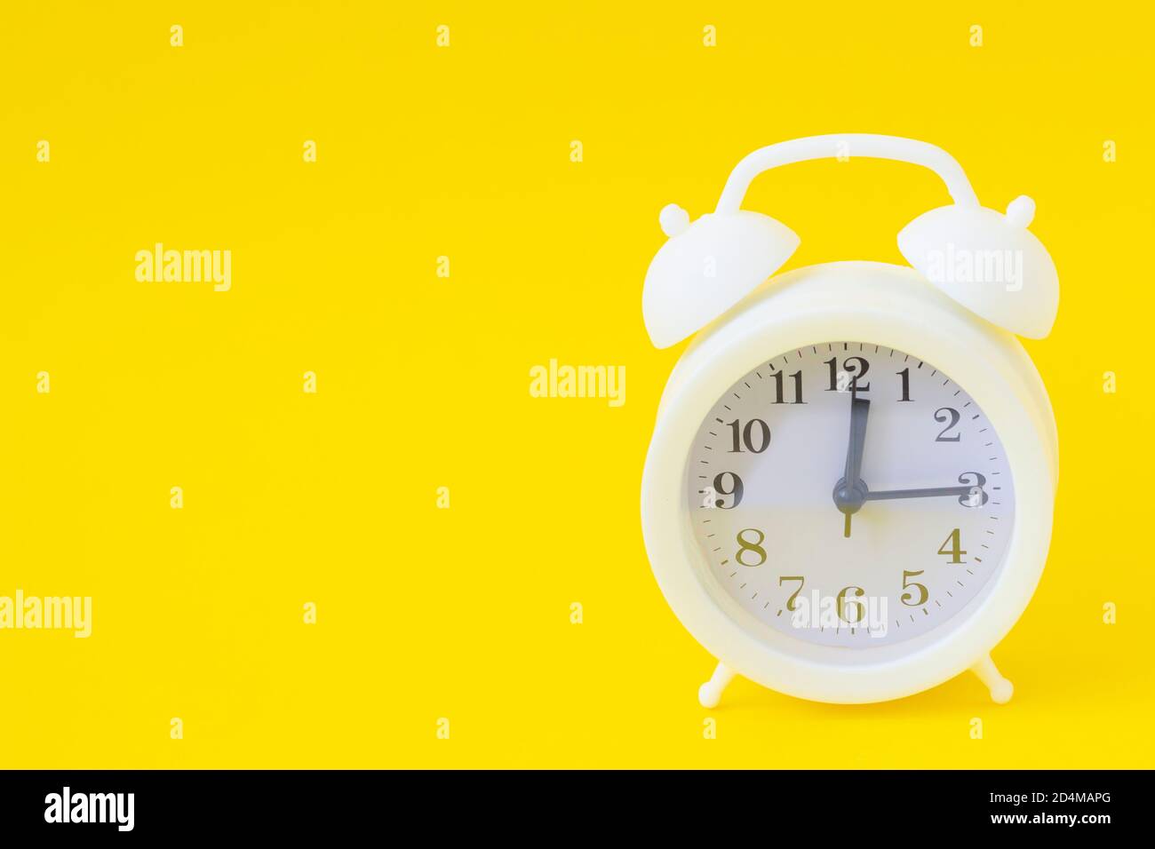 Weißer Wecker auf gelbem Hintergrund in Nahaufnahme. Platz kopieren, Banner. Stockfoto