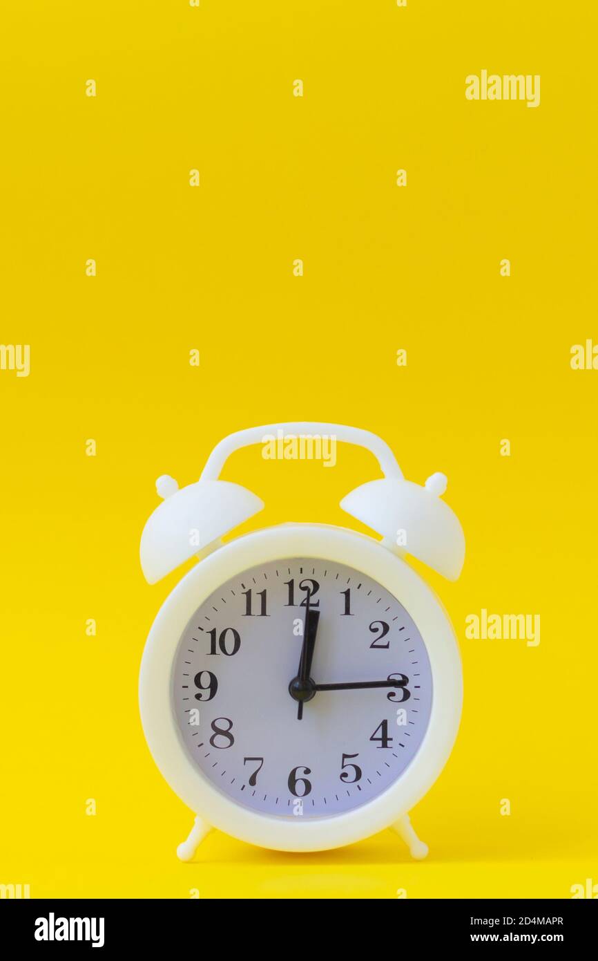 Weißer Vintage-Wecker auf einem hellgelben Hintergrund, Platz für Ihren Text, Kopierraum. Stockfoto