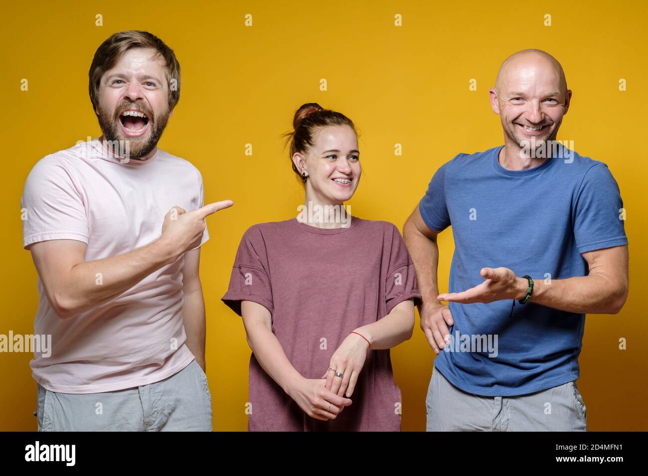 Nette, lustige Freunde, zwei Männer und eine Frau spielen auf der Party ein Spiel, lachen fröhlich und aufrichtig. Positive Emotionen. Stockfoto