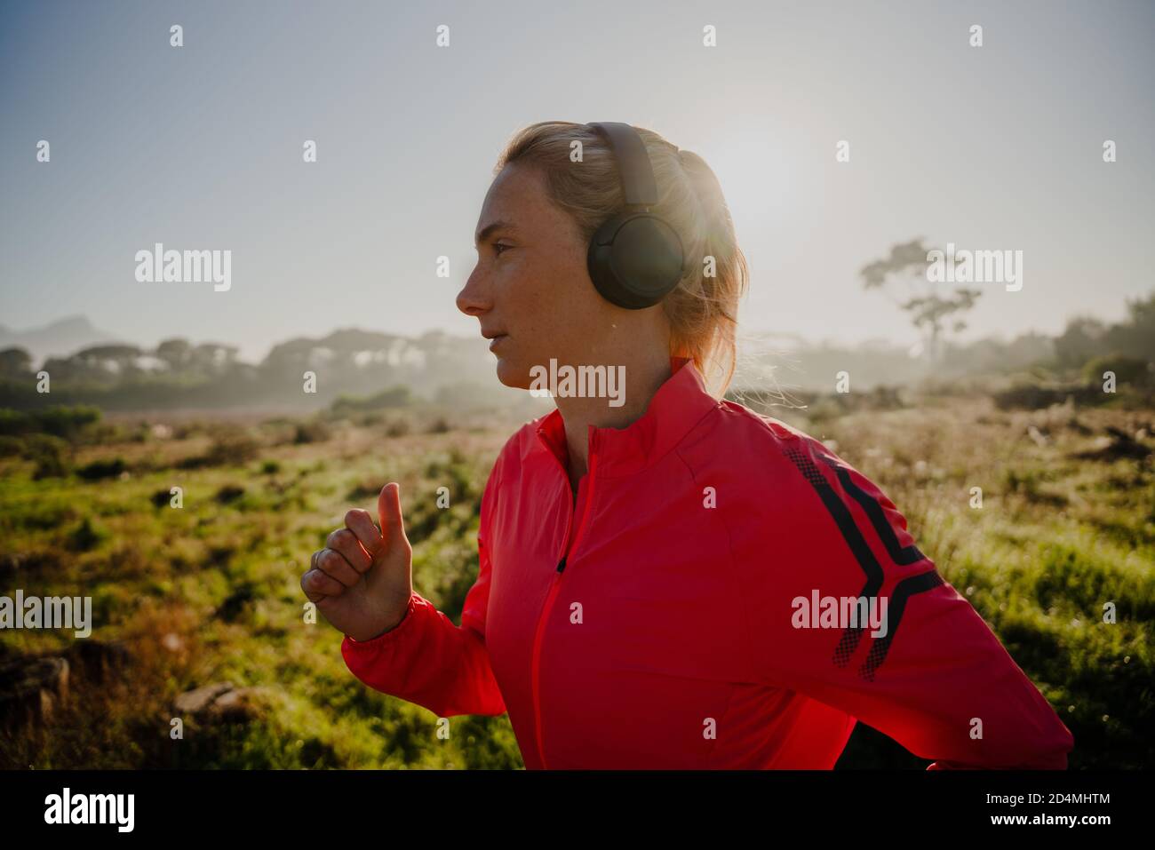 Athletische kaukasische Frau, die im Freien läuft und Musik mit Kopfhörern hört. Stockfoto