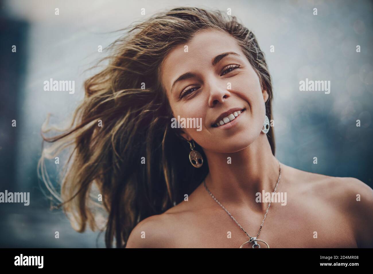 Junge lächelnde Frau windig draußen Portrait Stockfoto
