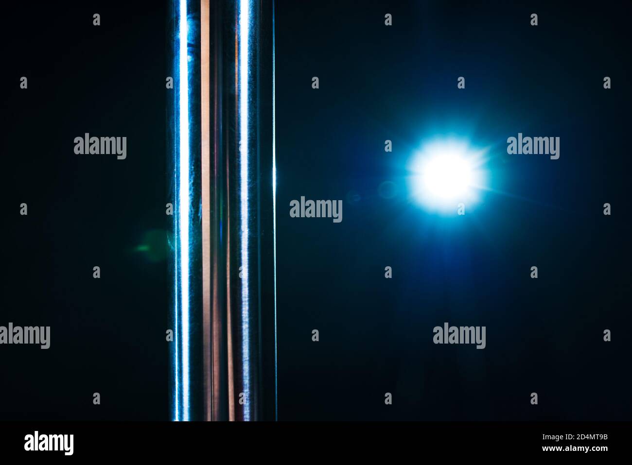 Metallic-Stangenschlosung und blaues Licht vom Blitz auf dunklem Hintergrund. Polentanz-Thema. Stockfoto
