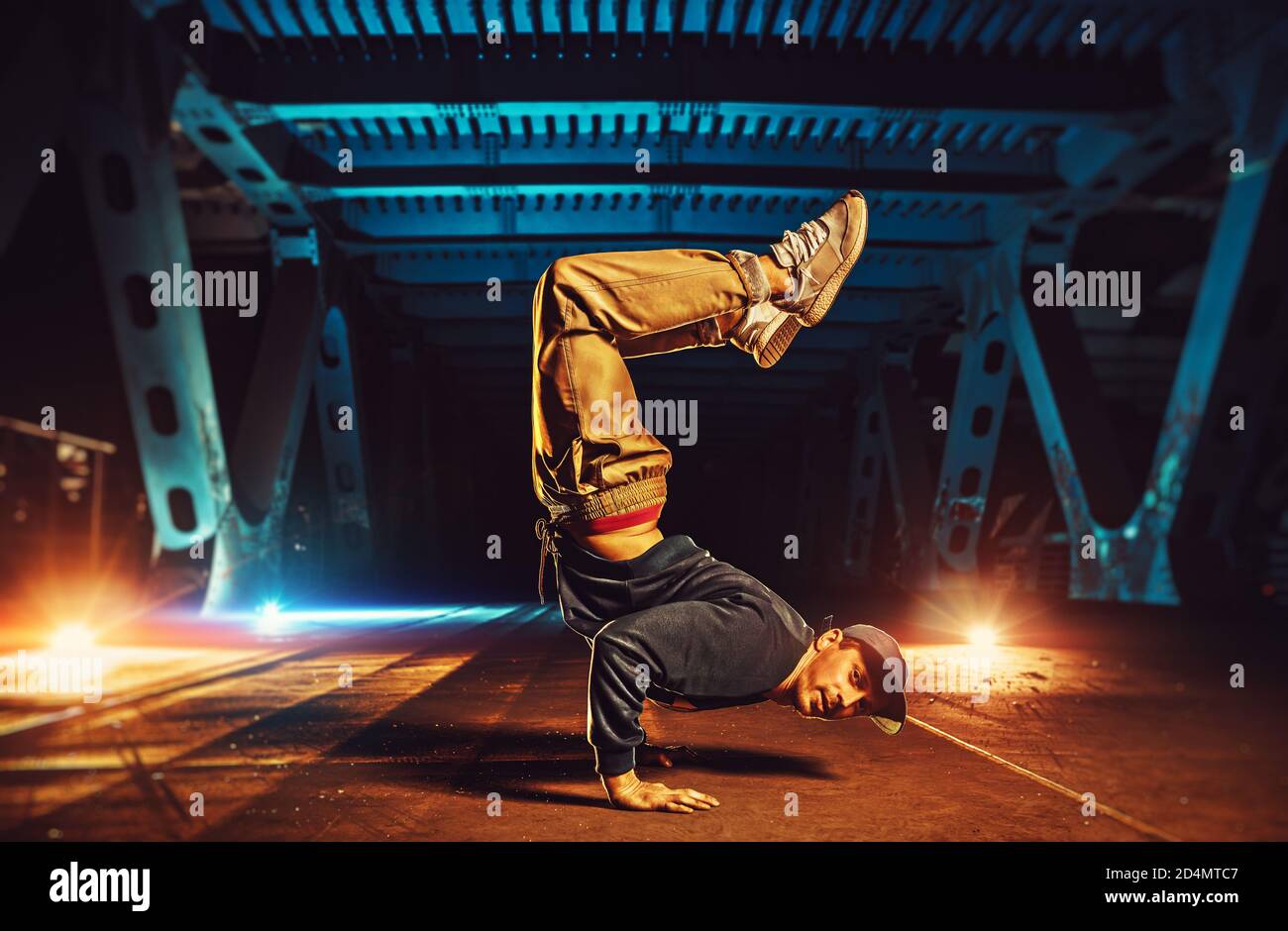 Junge coole Mann brechen Tänzer auf den Händen auf dem Kopf stehen. Urban Brücke mit kühlen und warmen Licht Hintergrund. Stockfoto