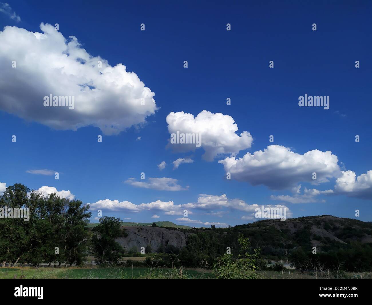 Himmel, Wolken, grüne Hügel und Bäume in Bulgarien. Wolkiger blauer Himmel. Stockfoto