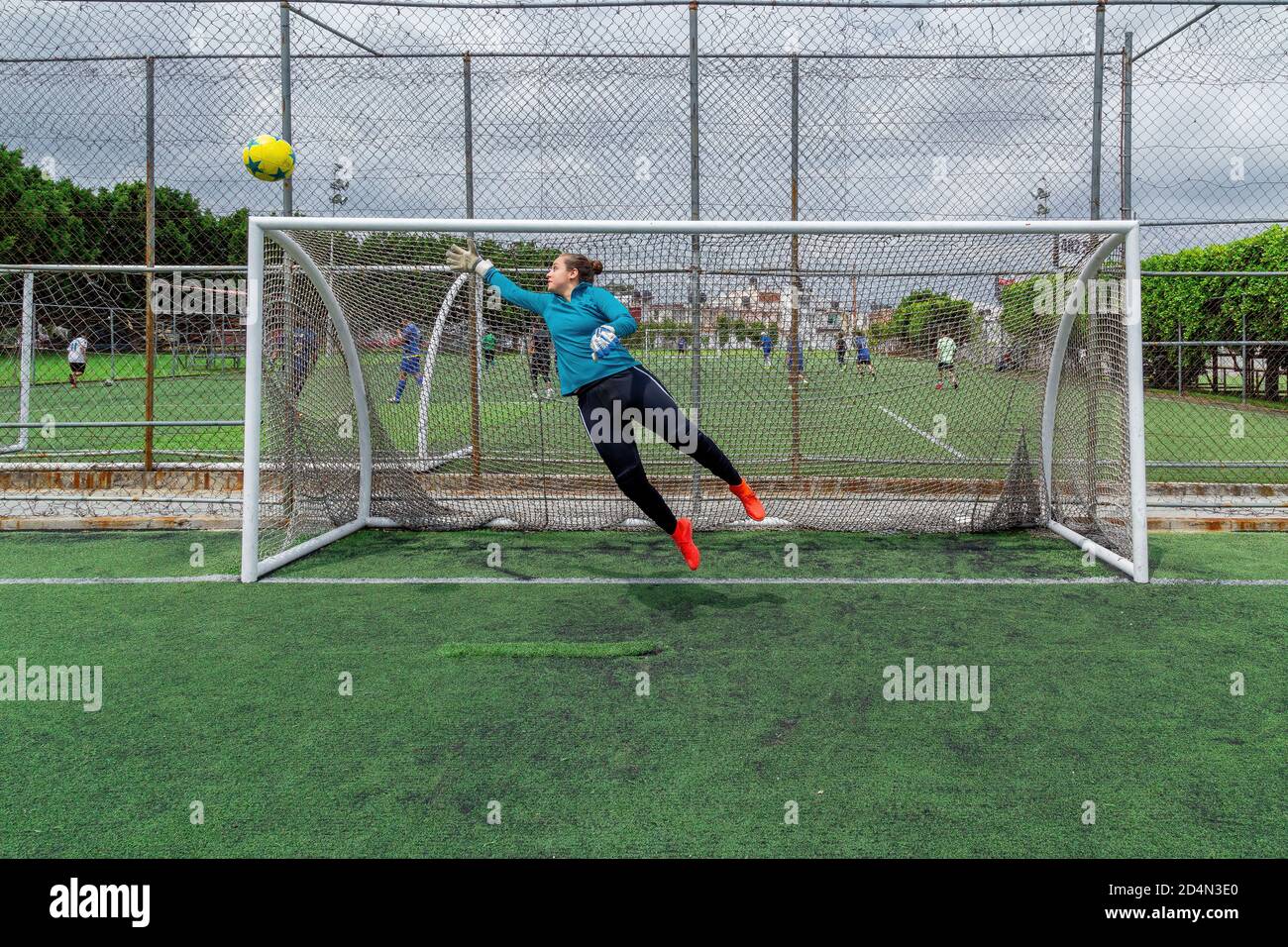Junge hispanische Torhüterin versucht, einen Ball zu fangen Stockfoto