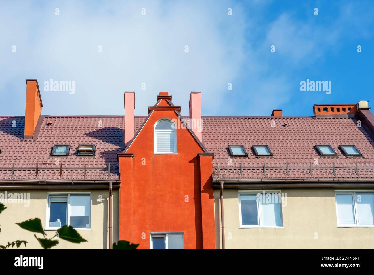 Dach eines Wohnhauses mit Dachgauben, Dachgeschoss Licht. Dachfenster, die helle Fassade eines Gebäudes in Europa. Stockfoto