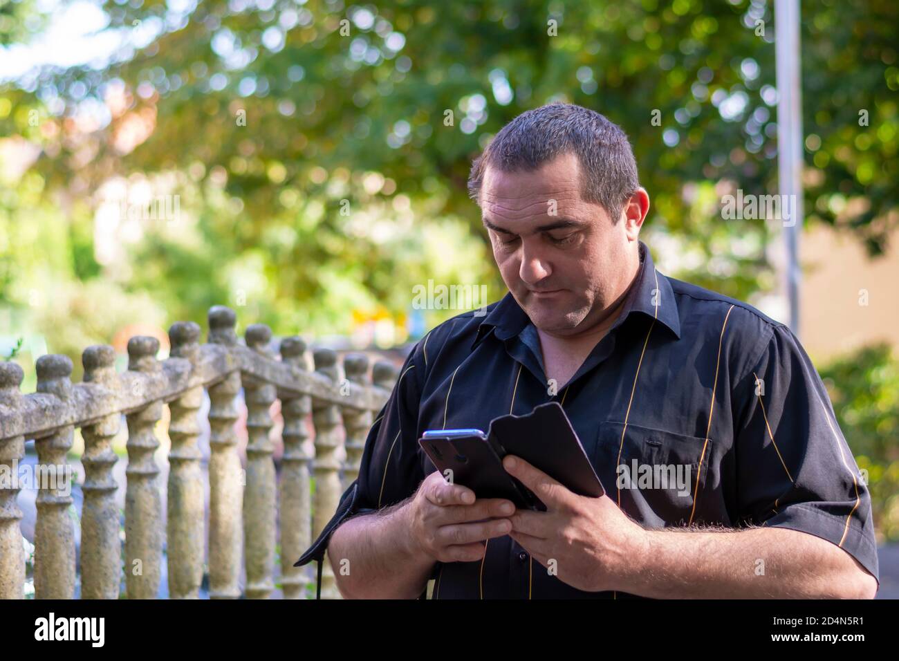 Der Mann auf der Straße schaut auf sein Smartphone und sucht einen Weg durch den Navigator in einer fremden Stadt. Stockfoto