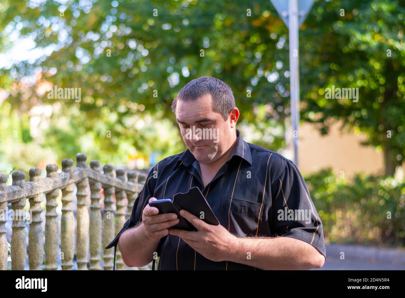 Kaukasischer Mann auf der Straße einer anderen Stadt schaut in ein Smartphone und sucht nach einem Weg durch eine Karte im Telefon. Stockfoto