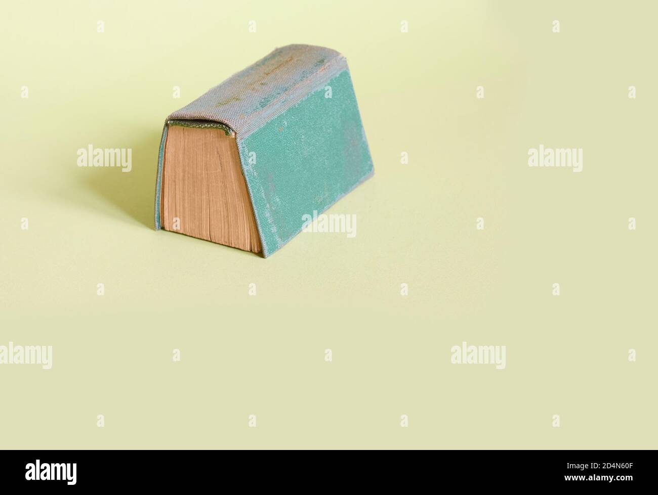 Das alte grüne Buch liegt auf einem schlichten grünen Hintergrund. Nahaufnahme Stockfoto