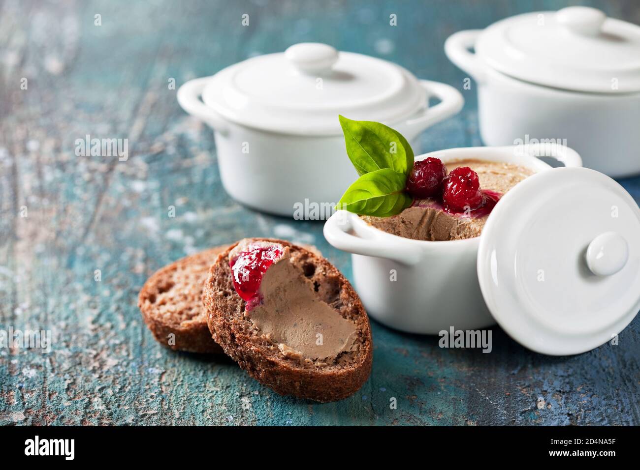 Frische hausgemachte Hähnchenleber-Pastete mit Cranberry-Sauce in keramischen Servierpfannen und Scheiben Keto-Brot, selektiver Fokus Stockfoto