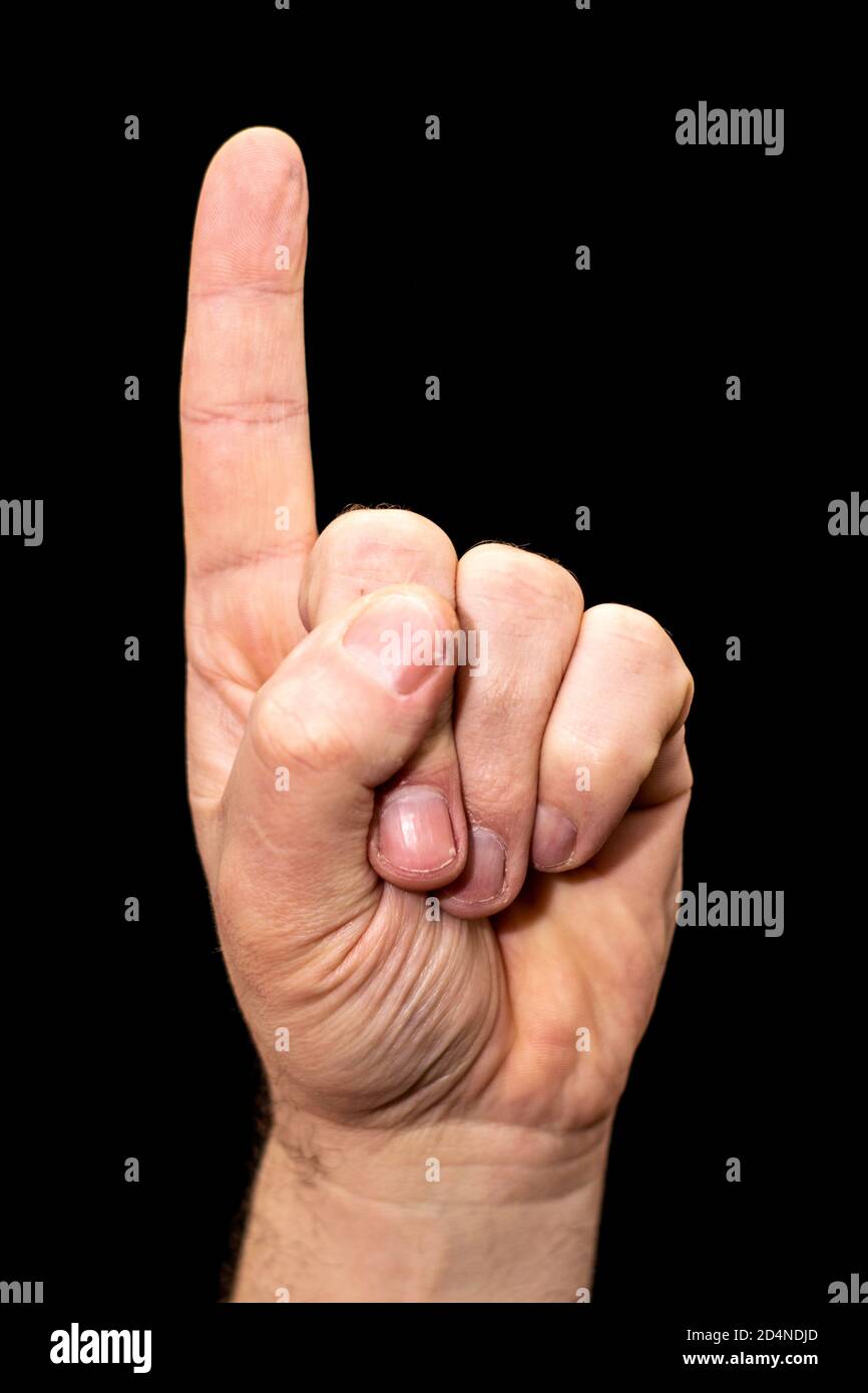 Männliche menschliche Hand auf schwarzem Hintergrund ein Zeigefinger zeigt Nach oben Stockfoto