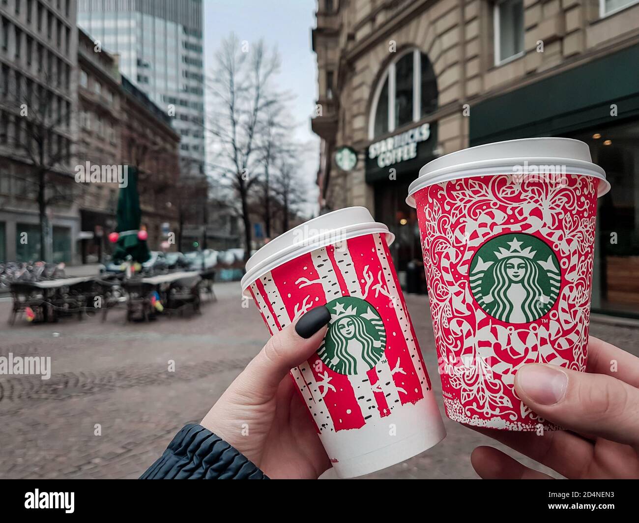 Köln / Deutschland - Neujahr 2018: Zwei Menschen halten Starbucks Weihnachtsfeiertage rote Tassen vor dem Café in Köln. Sonderedition Einweg-Becher Stockfoto