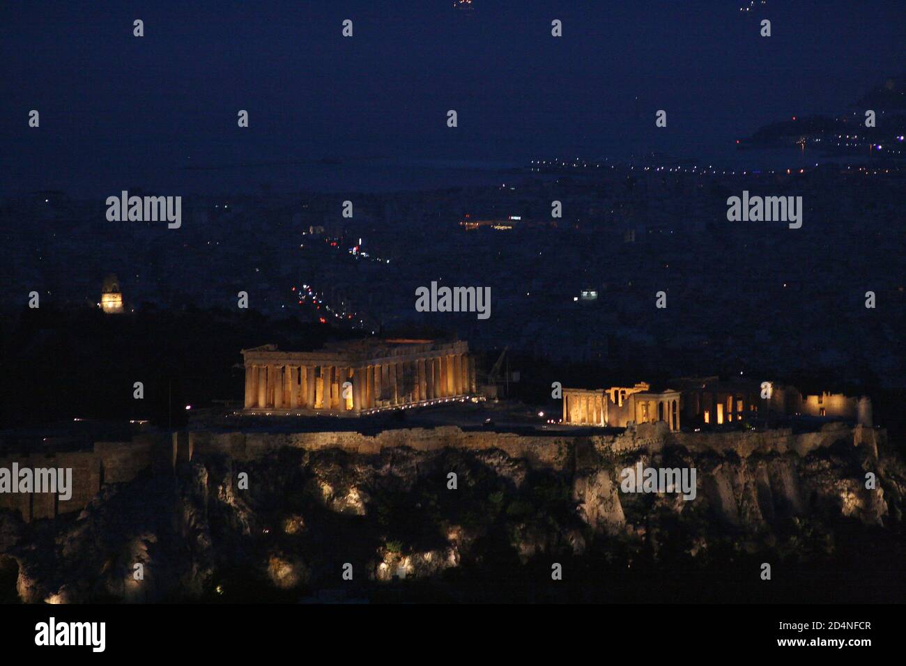 Nachtansicht von Athen. Die Akropolis von Athen und der Parthenon vom Mt. Lycabettus. Piräus Hafen im Hintergrund Stockfoto