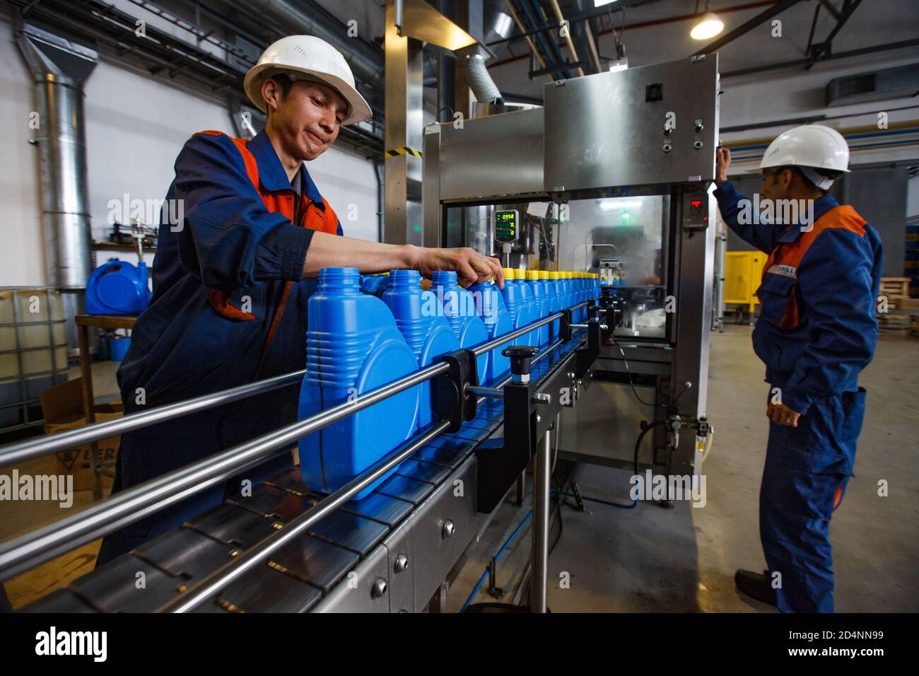 Shymkent, Kasachstan - April 26 2012: Moderne Motorenölanlage. Zwei Arbeiter an der Produktionslinie. Verpackungsöl in Kunststoff-kanister Stockfoto