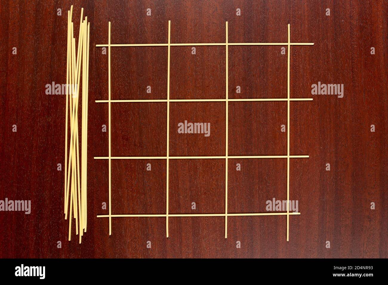 Italienische Pasta. Game Grid maade aus rohen Spaghetti für das Spielen Tic Tac Toe Spiel oder XS und OS. Die trockenen Capellini auf einem braunen Holztisch. Stockfoto