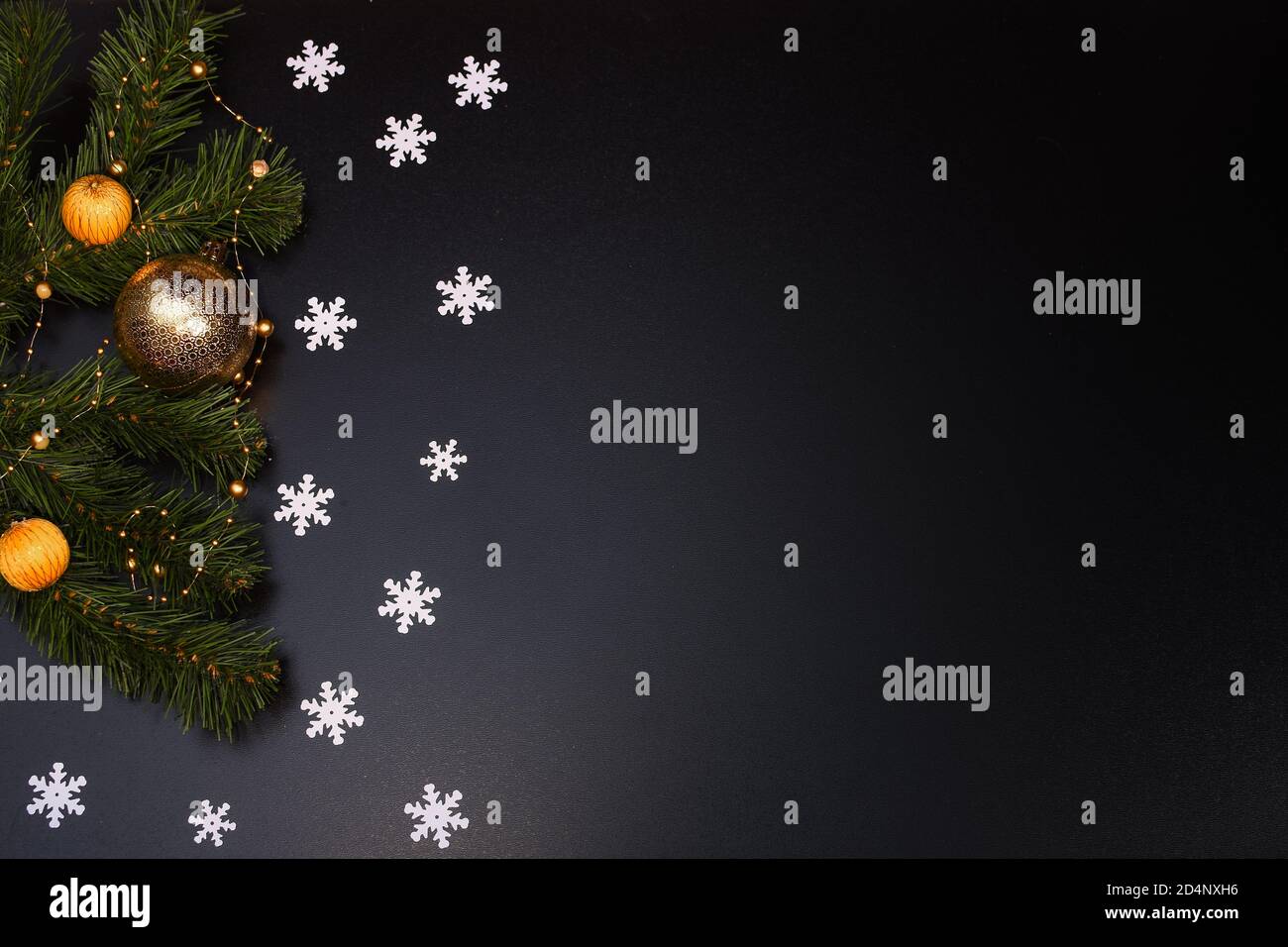 Weihnachtskomposition. Schneeflocken, Fichtenzweige, Weihnachtsspielzeug auf schwarzem Hintergrund. Stockfoto