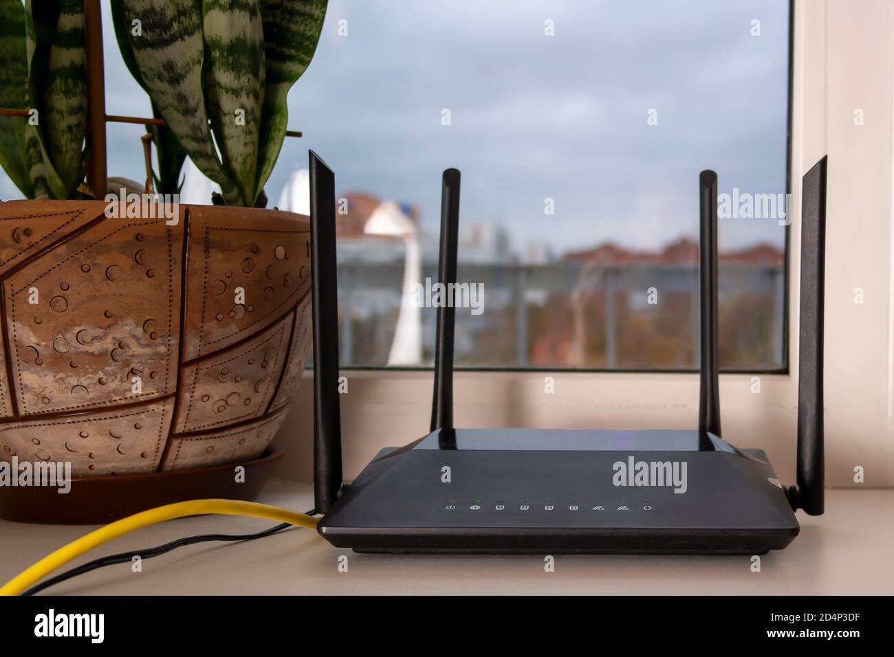 Auf der Fensterbank steht ein schwarzer WLAN-Router Stockfoto