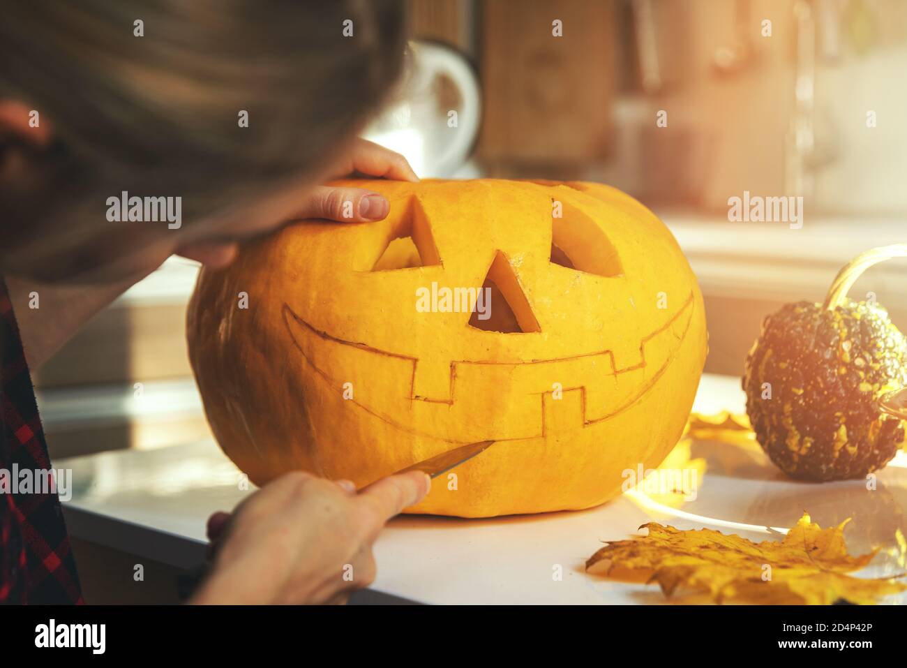 Frau, die Kürbis in Jack-o-Laterne für halloween-Feiertagsdekoration einschnitzt Wohnküche Stockfoto