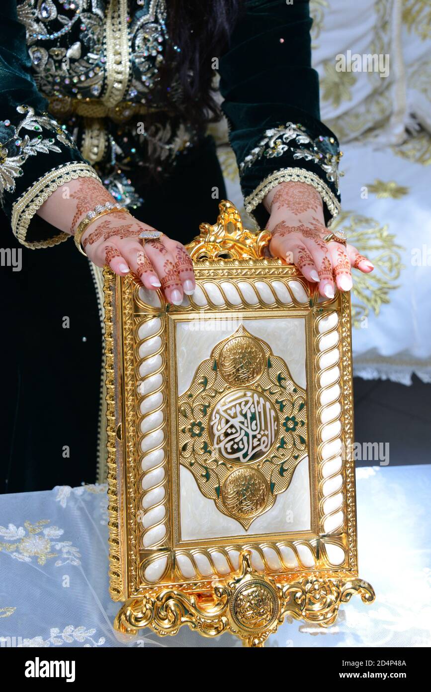 Marokkanisches Henna. Hand einer marokkanischen Braut tätowiert mit Henna hält den Heiligen Koran Stockfoto