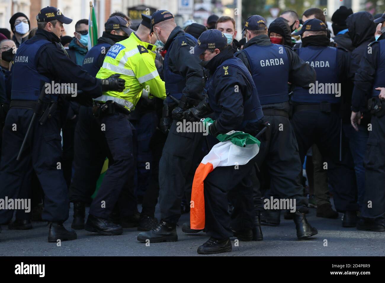 Mitglieder der Garda Public Order Unit entfernen während eines Anti-Lockdown-Protests vor dem Leinster House in Dublin eine irische Trikolore von den Gegendemonstrierenden, da Irland weiterhin landesweit an einer Stufe-3-Coronavirus-Sperre versperrt ist. Stockfoto