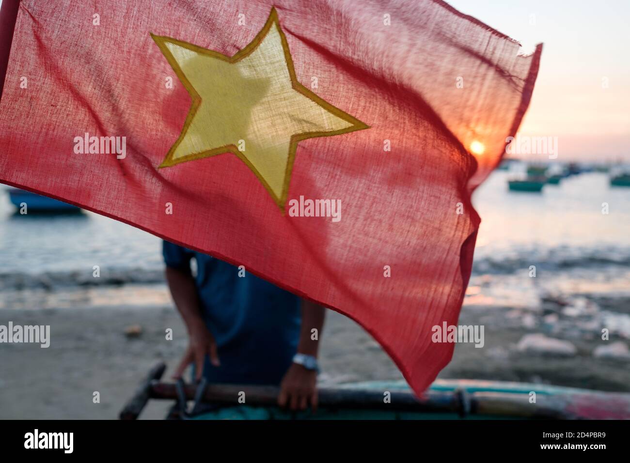Eine vietnamesische Flagge mit einem Fischer im Hintergrund Stockfoto