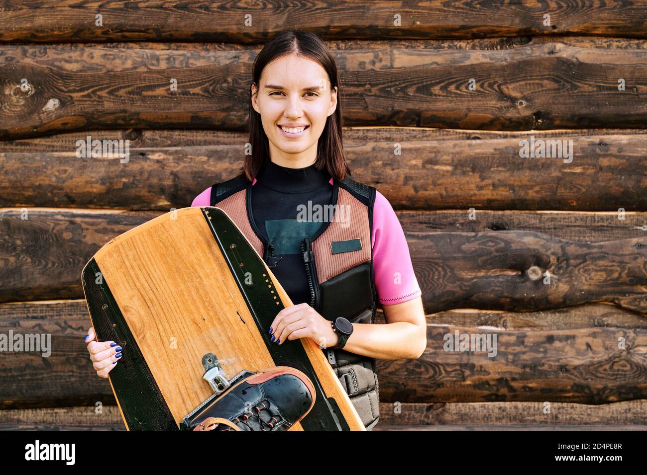 Aktive junge fröhliche weibliche Surfer in Sicherheitsjacke hält sie Surfbrett Stockfoto