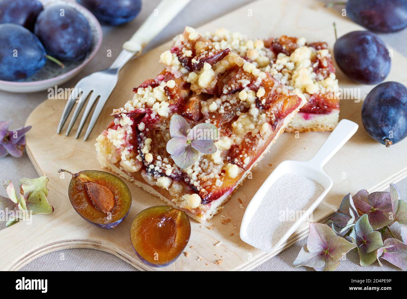 Pflaumenscheibe mit bröckelndem Belag auf Holzbrett Stockfoto