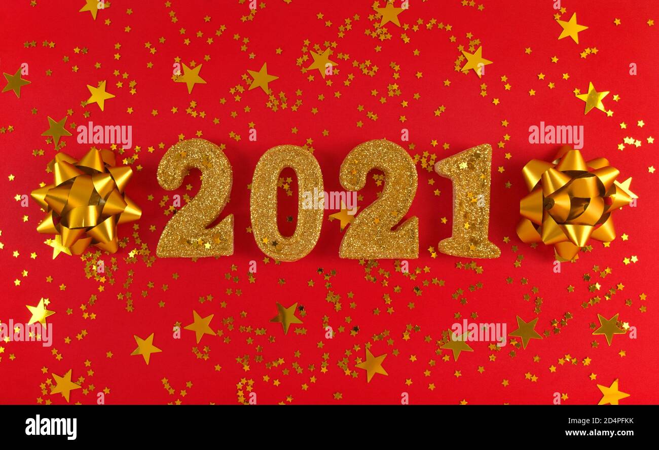Grußkarte des neuen Jahres 2021. Goldene glitzernde Figuren, Sterne und Bögen auf rotem Hintergrund. Stockfoto