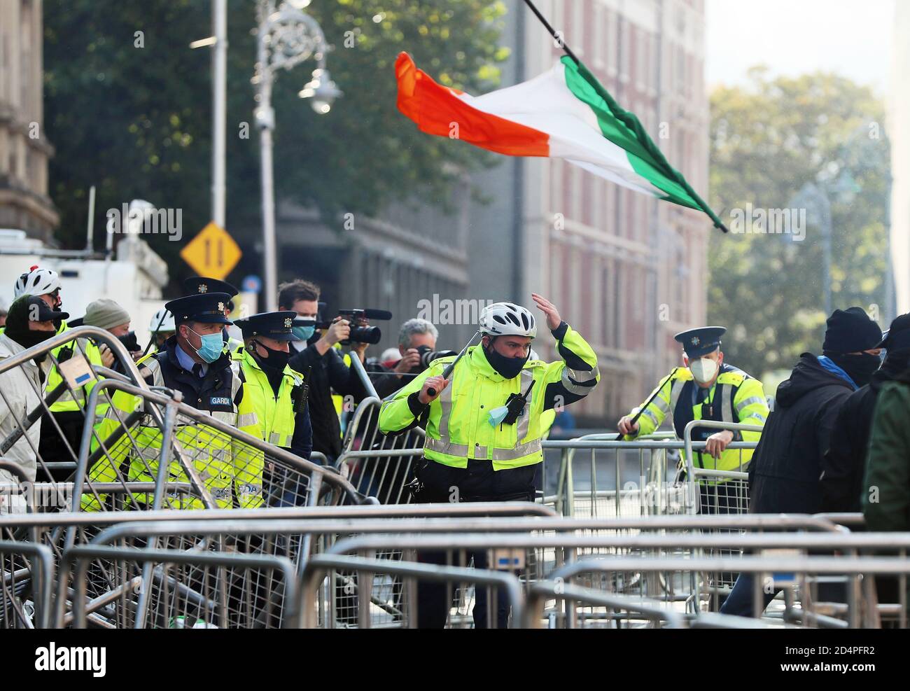 Eine irische Trikolore wird durch die Luft geworfen, während Mitglieder eines Garda eingreifen, während Anti-Lockdown-Demonstranten mit Gegendemonstranten während eines Anti-Lockdown-Protests vor dem Leinster House in Dublin zusammenprallten, da Irland weiterhin auf einer landesweiten Stufe-3-Coronavirus-Sperre ist. Stockfoto