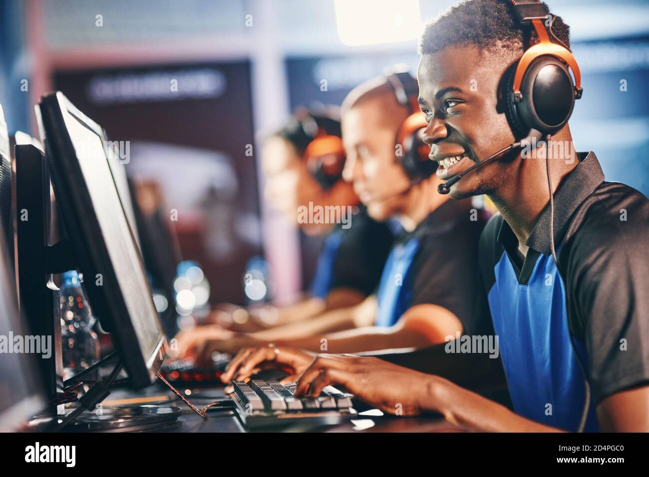 Professioneller Player. Seitenansicht eines jungen aufgeregt afrikanischen Kerl, männliche Cybersport-Gamer mit Kopfhörern spielen Online-Videospiele, während die Teilnahme mit Team in eSport Turnier Stockfoto