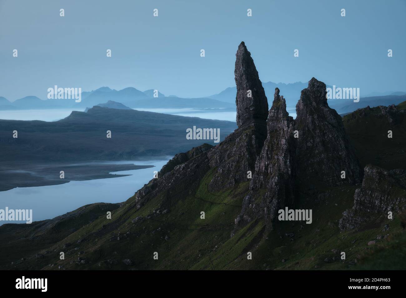 Atemberaubende Aussicht auf den großen Felsengipfel, der über einem See und dem Meer vor Sonnenaufgang thront. The Old man of Storr, Isle of Skye, Schottland, Großbritannien Stockfoto