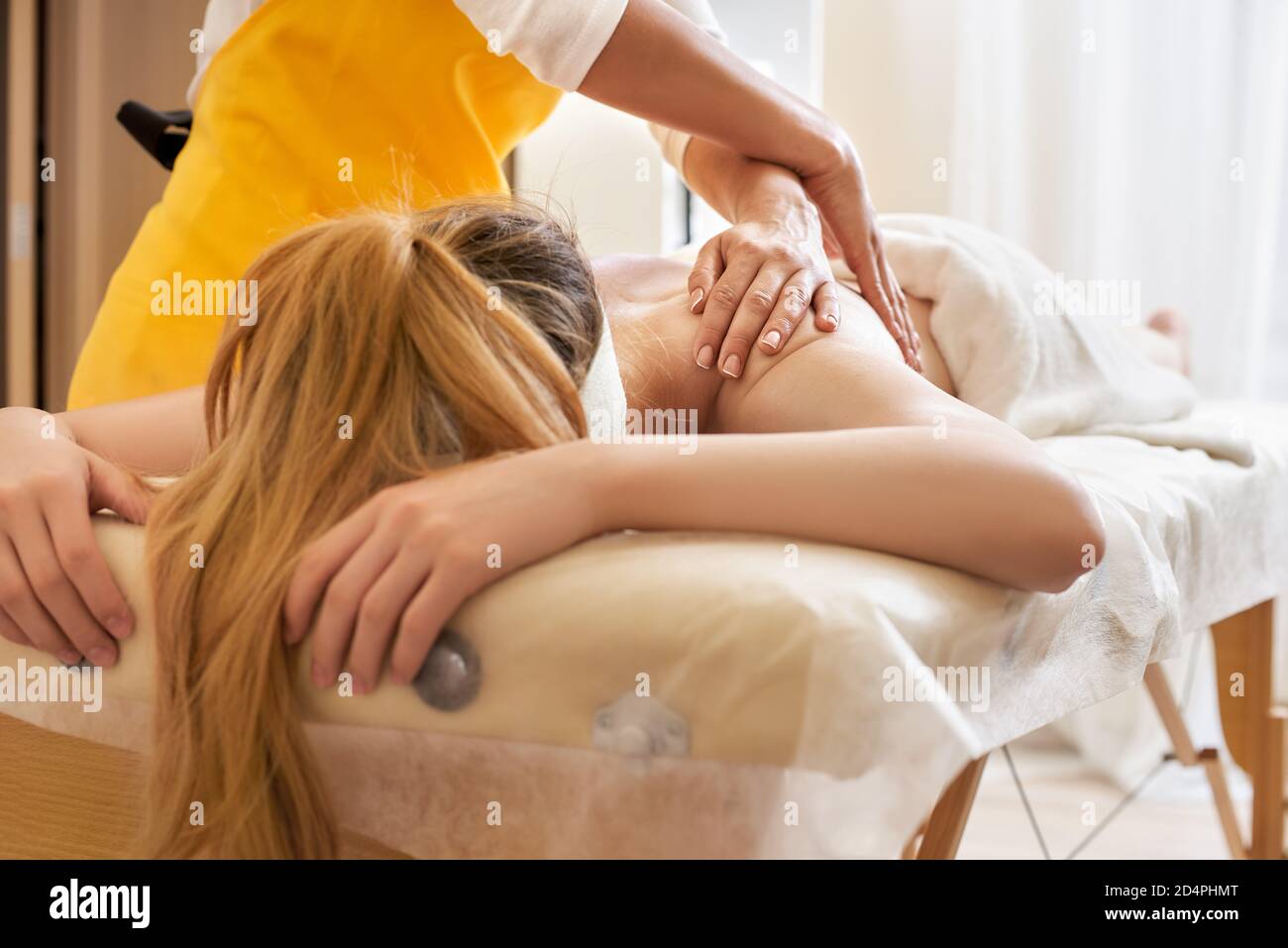 Junge Frau erhält eine Rückenmassage in einem medizinischen Zentrum. Weibliche Patientin wird von einem professionellen Therapeuten mit schönen Händen behandelt. Körper Stockfoto