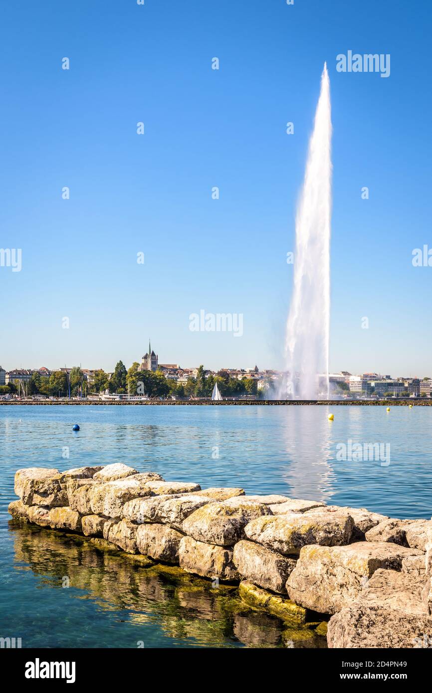 Die Stadt und Bucht von Genf, Schweiz, von einem Steinsteg aus gesehen von einem sonnigen Sommermorgen mit der Kathedrale und dem Jet d'Eau, der 140 Meter hohen Waa Stockfoto