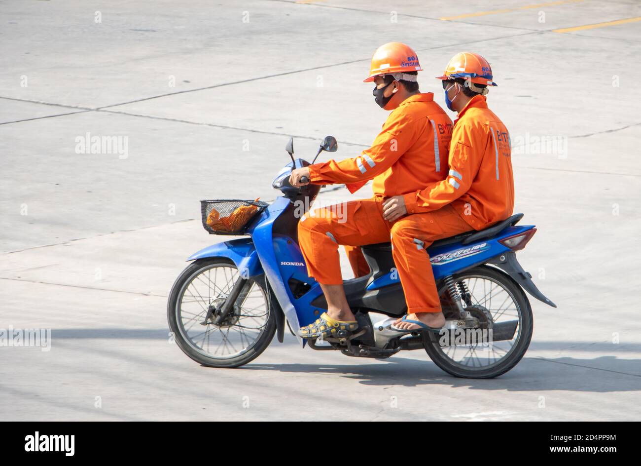 SAMUT PRAKAN, THAILAND, 29 2020. JULI, zwei Männer in den orangen Overalls fahren ein Motorrad. Stockfoto