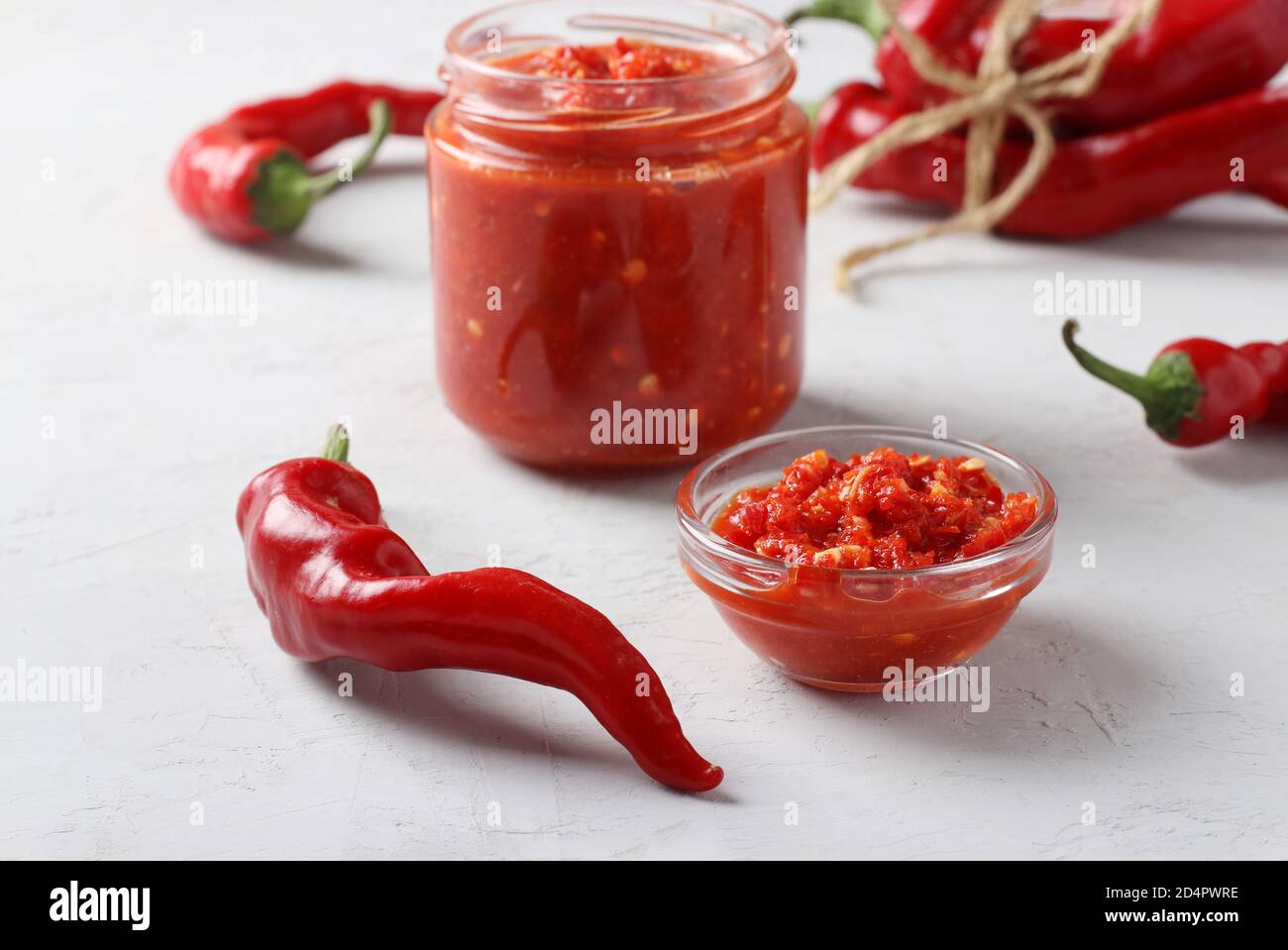 Traditionelle Soße Adjika mit scharfem Chili, Paste Harissa auf hellem Hintergrund. Tunesische, georgische und arabische Küche. Horizontales Format. Nahaufnahme Stockfoto