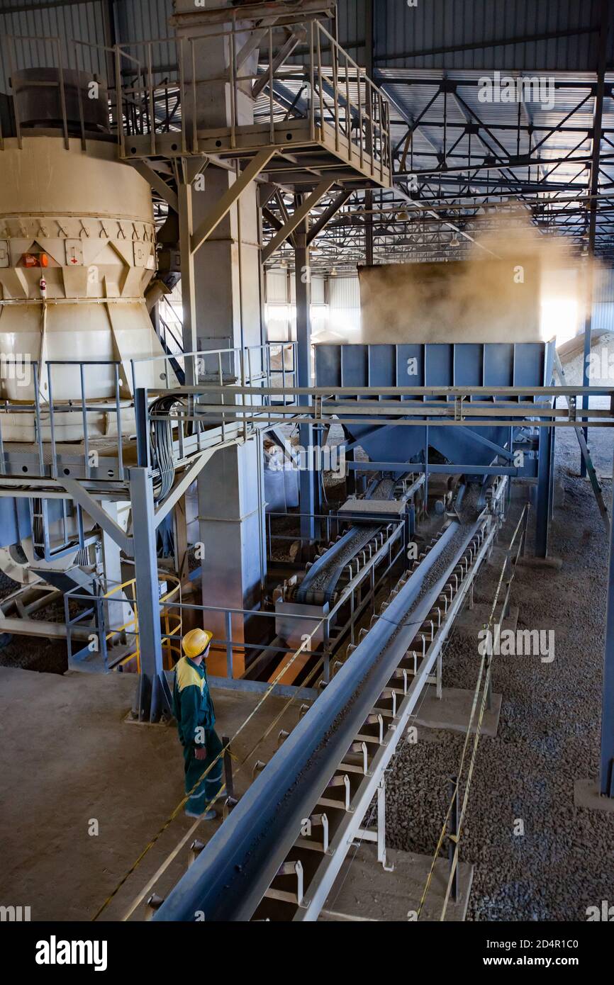 Region Aktobi/Kasachstan - Mai 04 2019: Phosphatdüngeanlage. Maschine für Pellets Produktion. Bediener in gelben Helm steuert Prozess. Stockfoto