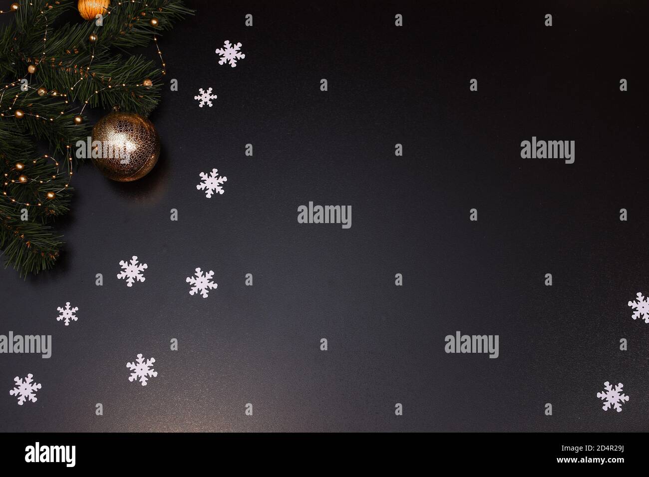 Weihnachtskomposition. Weiße Schneeflocken, Fichtenzweige, Weihnachtsspielzeug auf schwarzem Hintergrund. Platz für eine Inschrift. Stockfoto